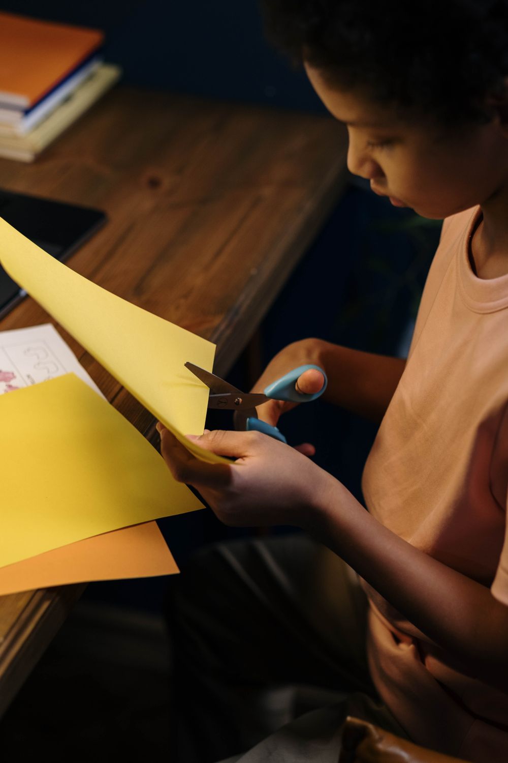 Dziecko trzyma żółty papier i wycina go nożyczkami